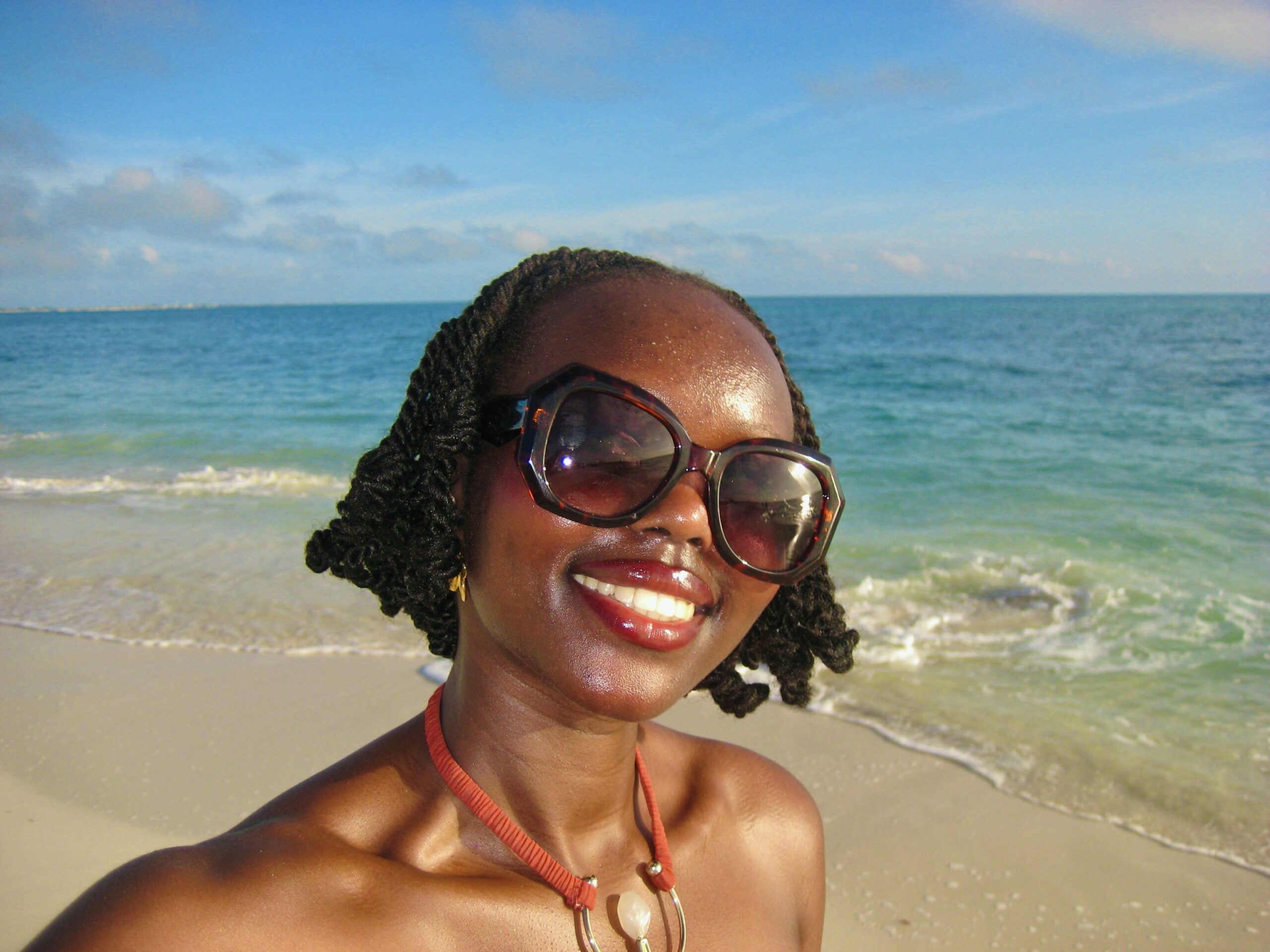 Author smiling at the beach with sea backdrop